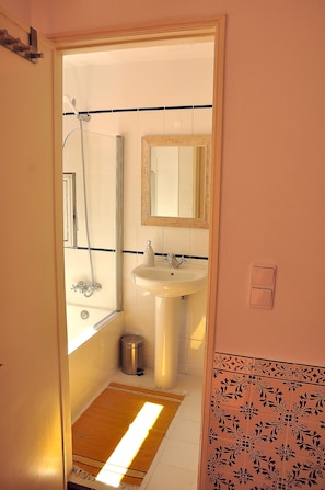 A bathroom with a shower, sink, and mirror.