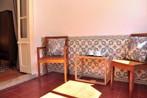 A corner room with two wooden chairs, a small table, and patterned tile walls. - Comfortable and stylish apartment, fully equipped, in Lapa in Lisbon (Lisboa ciudad)