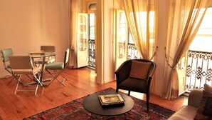 A living room with a glass table, two chairs, a sofa, a patterned rug, and a balcony with curtains. - Comfortable and stylish apartment, fully equipped, in Lapa in Lisbon (Lisboa ciudad)