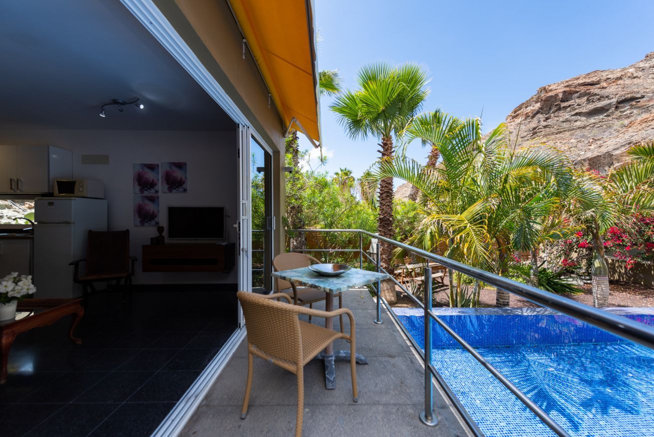 Un balcone con piscina, sedie e tavolo da pranzo.