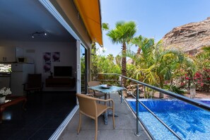 Un balcón con piscina, sillas y una mesa de comedor.