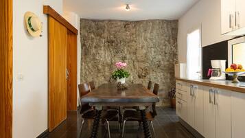 A modern kitchen with a stone accent wall, wooden cabinets, and a dining table with chairs.