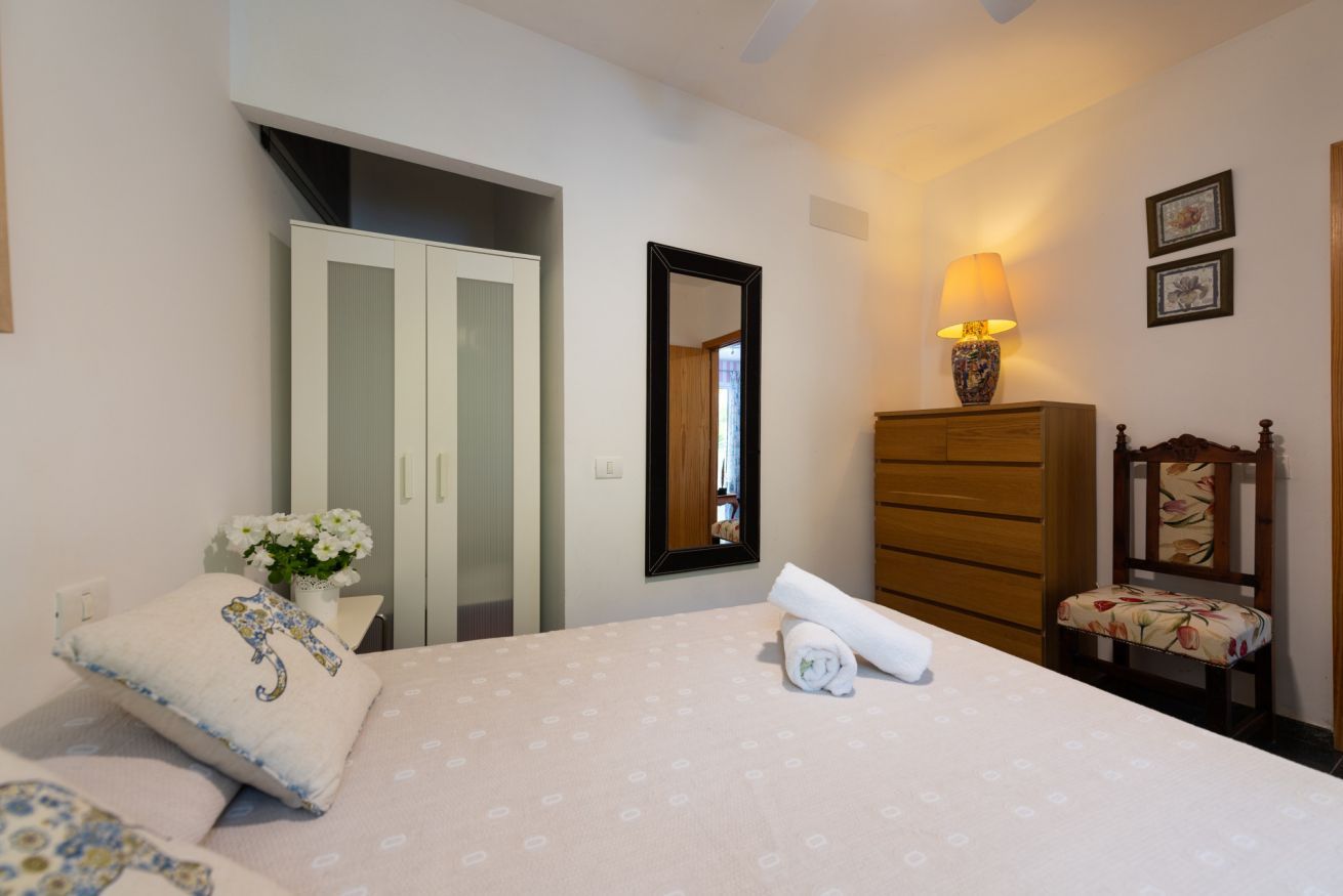 Een slaapkamer met een bed, een kaptafel, een stoel, een spiegel en een lamp.