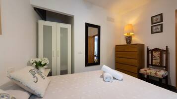 Een slaapkamer met een bed, een kaptafel, een stoel, een spiegel en een lamp.