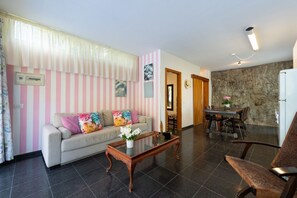 A living room with a sofa, coffee table, and dining area with chairs and a table.