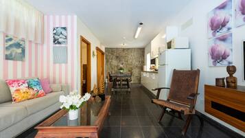 A modern living room with a sofa, coffee table, and a dining area with a table and chairs.