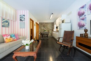 A modern living room with a sofa, coffee table, and a dining area with a table and chairs.