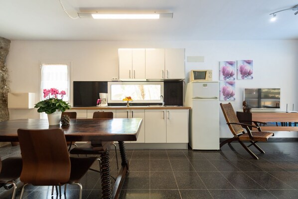 A modern kitchen with white cabinets, a microwave, and a dining area with a table and chairs.