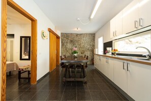 A modern kitchen with a stone accent wall, a dining table with chairs, and a built-in oven.