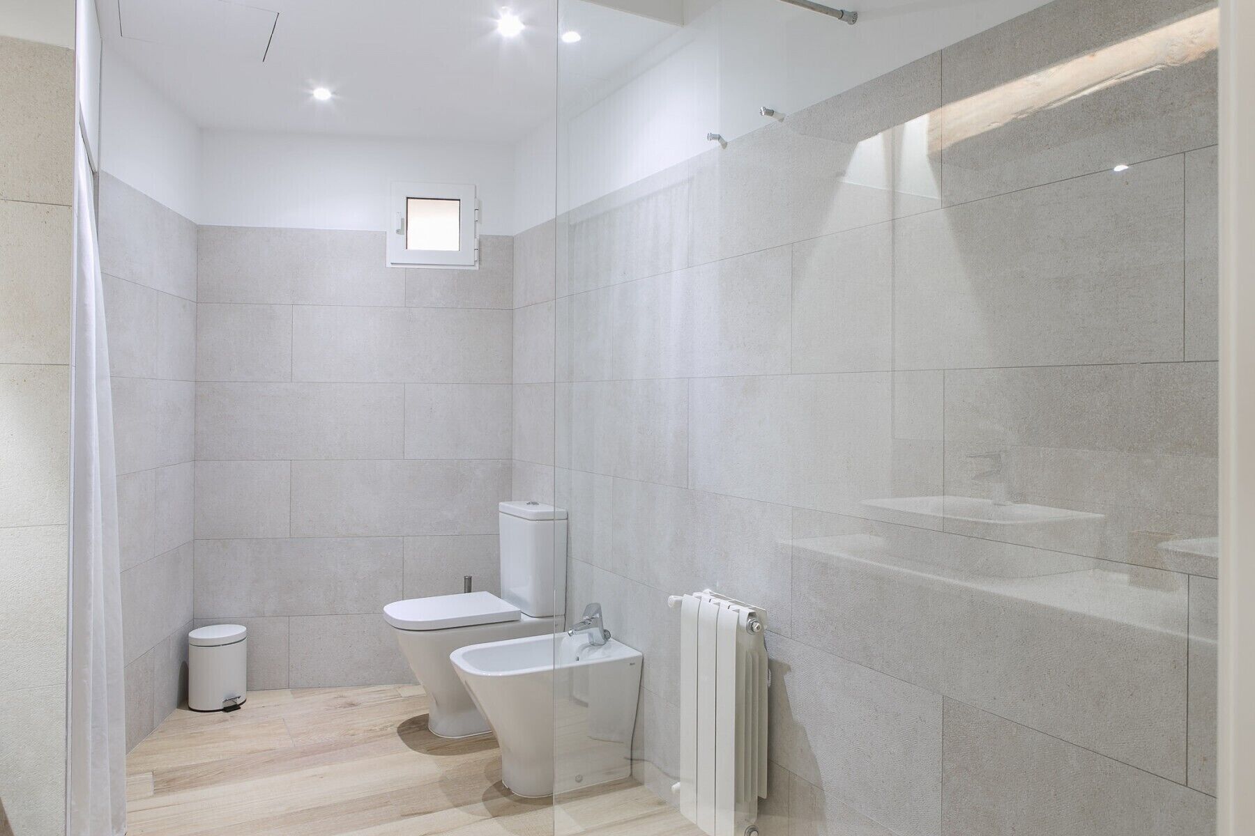 Ein modernes Badezimmer mit Dusche, Toilette, Bidet und Handtuchwärmer.
