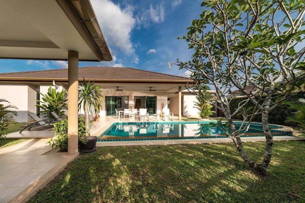 Une maison moderne dotée d’une piscine, d’un patio couvert et d’une végétation luxuriante.