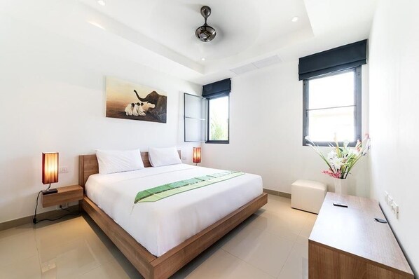 A modern hotel room with a large bed, bedside lamps, a desk, and a painting on the wall. - Asia Baan 10 pool Villas (Choeng Thale)