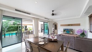 Una sala de estar moderna con comedor, ventanas amplias y vista a la piscina.