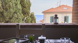 Una mesa con un juego de té y vasos, con vista a un edificio de tejas y al mar.