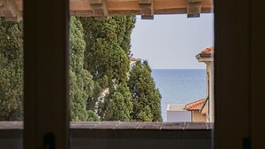 Vista a través de una ventana con marco de madera, sobre un cuerpo de agua y un edificio con techo de tejas.