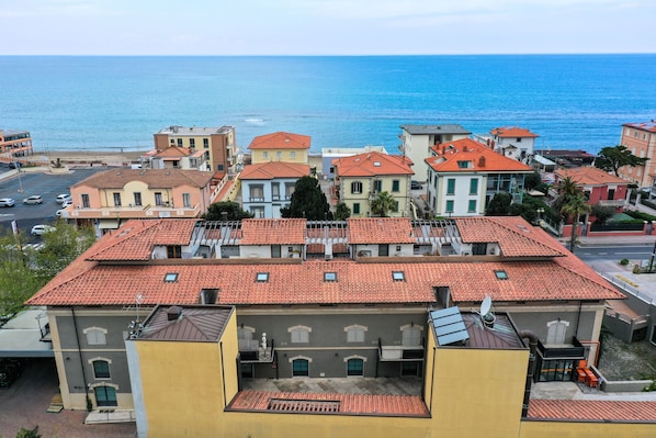 A coastal town with buildings featuring red-tiled roofs and a view of the sea.