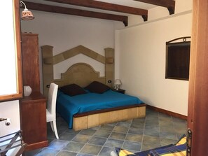 A bedroom with a bed, a nightstand, a lamp, and a window. - Villa in Lampedusa for two people,<br>proprietary<br>Nunzia (Lampedusa)