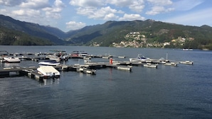 A marina with boats docked, surrounded by mountains and a small town in the background.