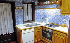 Kitchen features a dishwasher, oven, and gas stove, with blue and white patterned tiles and a wooden cabinet.
