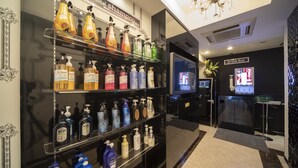A hotel lobby with a reception desk, a drink bar, and shelves of toiletries. - HOTEL G-Style - Adults Only (Tokyo)