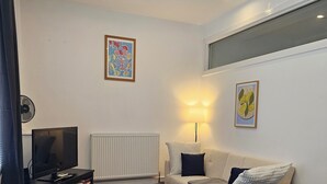 Ein modernes Wohnzimmer mit einer Couch, einem Fernseher, einer Lampe und Kunstwerken an den Wänden.