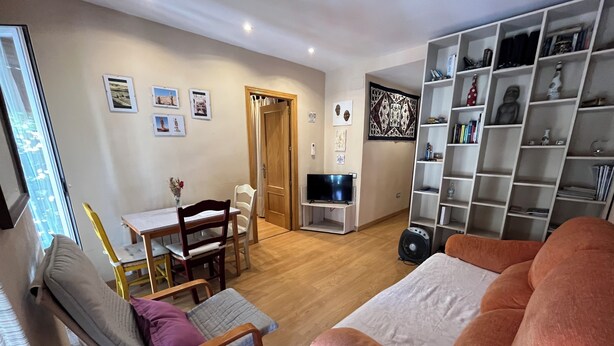 A living room with a sofa, a dining table with chairs, a TV, and a bookshelf. - 2 Bedroom Apartament for rent next Atocha St. (Madrid)
