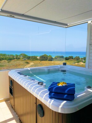 A hot tub with a view of the ocean, a blue towel, and a flower on the edge.