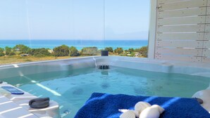 A hot tub with a view of the ocean, a towel, and seashells. - Seabreeze, a new luxury seafront villa for up to 9 people (Mastichari)