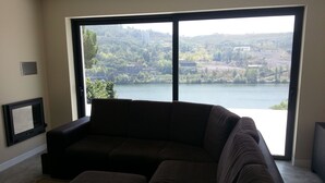 A living room with a large window offering a view of a lake and hills.