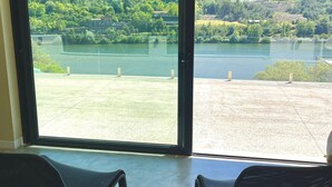 A room with two black chairs facing a large window overlooking a lake and hills.