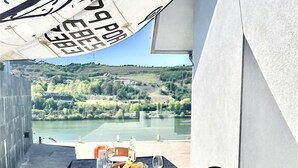 A dining area with a table set for two, overlooking a scenic view of a lake and hills.
