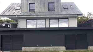 A modern house with a swimming pool, large windows, and garage doors.