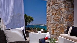 A balcony with wicker furniture, white cushions, and a stone wall. - Villa Meadow 5 pax Private Infinity Pool  Beach Hotel Villa Paradise Naxos  (Naxos)