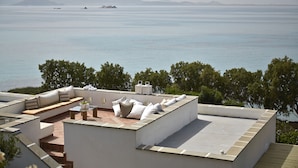 A rooftop terrace with a seating area, a small table, and a view of the sea and distant islands. - Villa 'Blue' 10 pax Private Infinity Pool Beach Hotel Villa Paradise Naxos  (Naxos)