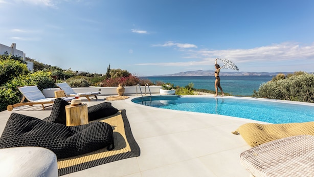 A poolside area with lounge chairs, a pool, and a view of the sea. - Villa 'Blue' 10 pax Private Infinity Pool Beach Hotel Villa Paradise Naxos  (Naxos)