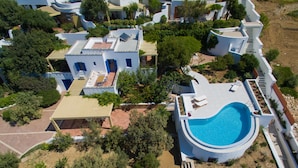 An aerial view of a residential area with multiple houses, a swimming pool, and surrounding greenery. - Villa 'Blue' 10 pax Private Infinity Pool Beach Hotel Villa Paradise Naxos  (Naxos)