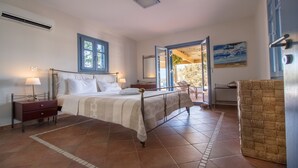 A bedroom with a bed, bedside tables, a window, and a view of the outdoors. - Villa 'Blue' 10 pax Private Infinity Pool Beach Hotel Villa Paradise Naxos  (Naxos)