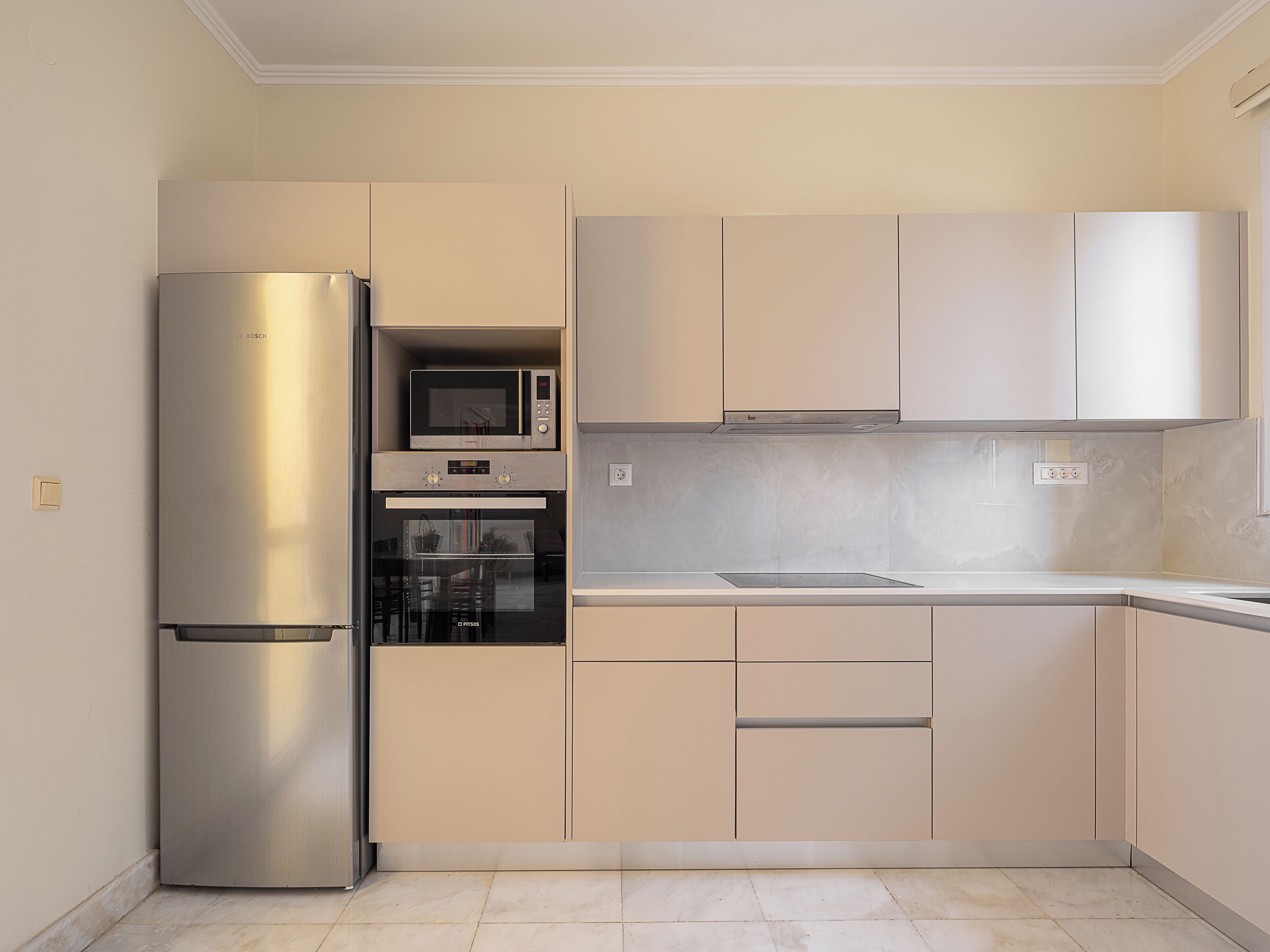 Una cocina con refrigerador de acero inoxidable, microondas integrado y horno doble.