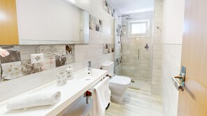 Een moderne badkamer met een douchecabine van glas, een toilet en een wastafel met een spiegel erboven.