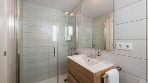 A modern bathroom with a glass shower enclosure, a wooden vanity with a white sink, and a large mirror. - Nice duplex in the center of Terrassa (Barcelona) (Terrassa)