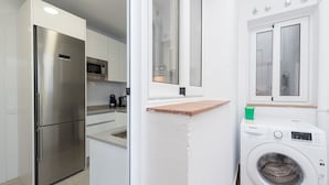 A compact kitchen with a stainless steel refrigerator, a microwave, and a washing machine. - Nice duplex in the center of Terrassa (Barcelona) (Terrassa)