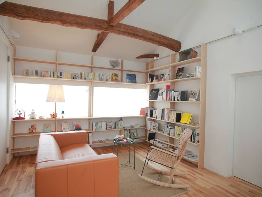 A cozy reading nook with a wooden rocking chair, a cushioned bench, and a bookshelf filled with books.