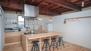 Una cocina moderna con armarios de madera, una isla grande con taburetes, electrodomésticos de acero inoxidable e iluminación colgante.