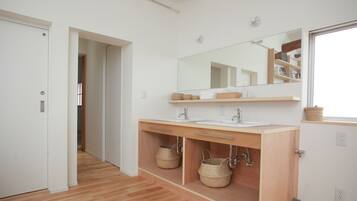Un baño moderno con tocador de madera, un espejo grande y una ducha a ras de suelo.