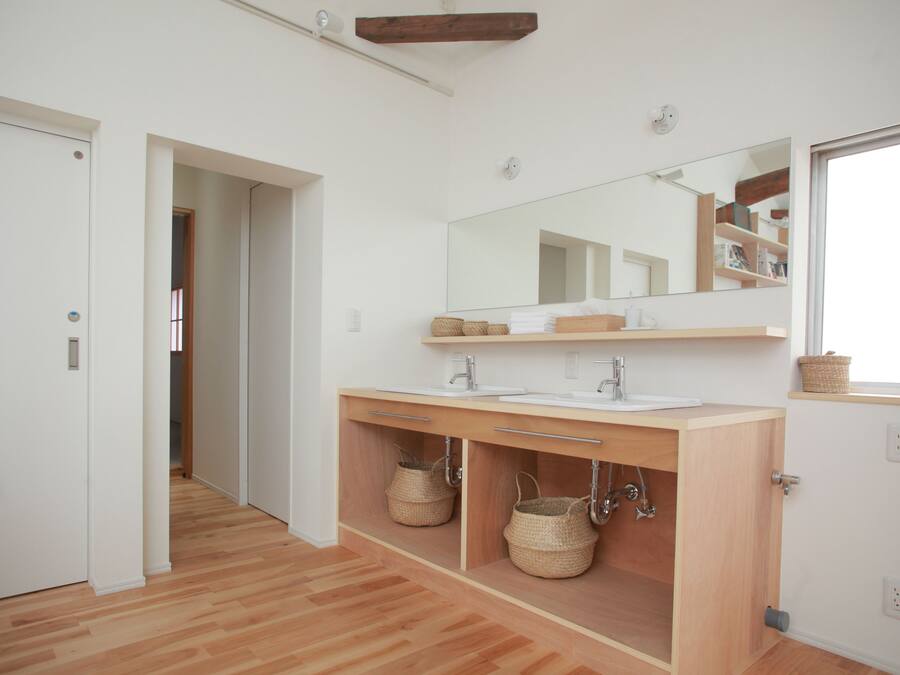 Un baño moderno con tocador de madera, un espejo grande y una ducha a ras de suelo.