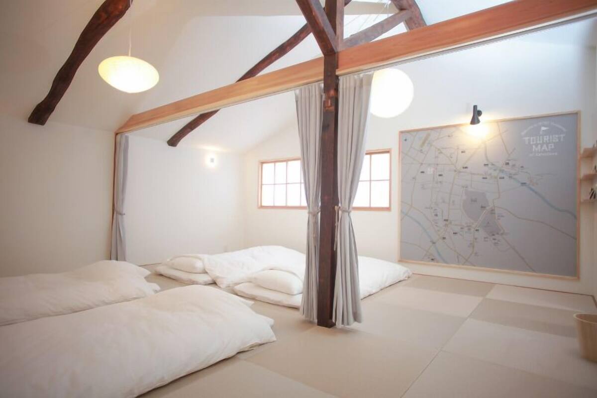 A room with a bed, a map on the wall, and a window.