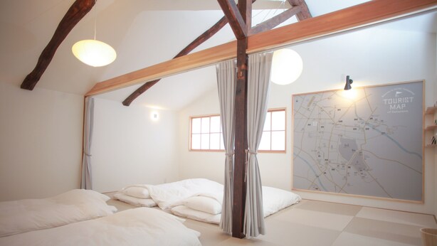 Una habitación con una cama grande, un mapa en la pared y una viga de madera en el techo.