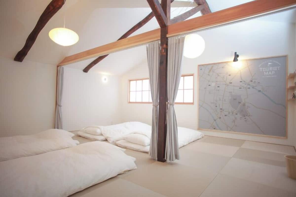 A room with a bed, a map on the wall, and a window.