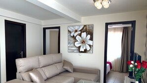A modern living room with a beige sofa, a glass coffee table, and a large floral artwork on the wall. - Apartment,  EXCELLENT LOCATION-NEXT TO THE BEACH-IDEAL FOR FAMILIES (Costa Calma)