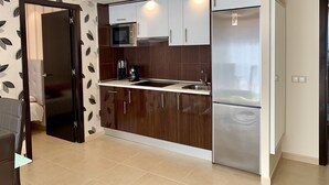 A modern kitchen with dark wooden cabinets, a stainless steel refrigerator, a microwave, and a coffee maker. - Apartment,  EXCELLENT LOCATION-NEXT TO THE BEACH-IDEAL FOR FAMILIES (Costa Calma)